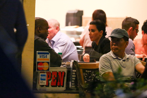 Kanye West e Kim Kardashian aguardam pela sua vez à porta de restaurante.