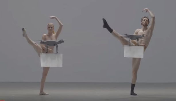 Par de bailarinos dançam completamente nus, tapados apenas por drones