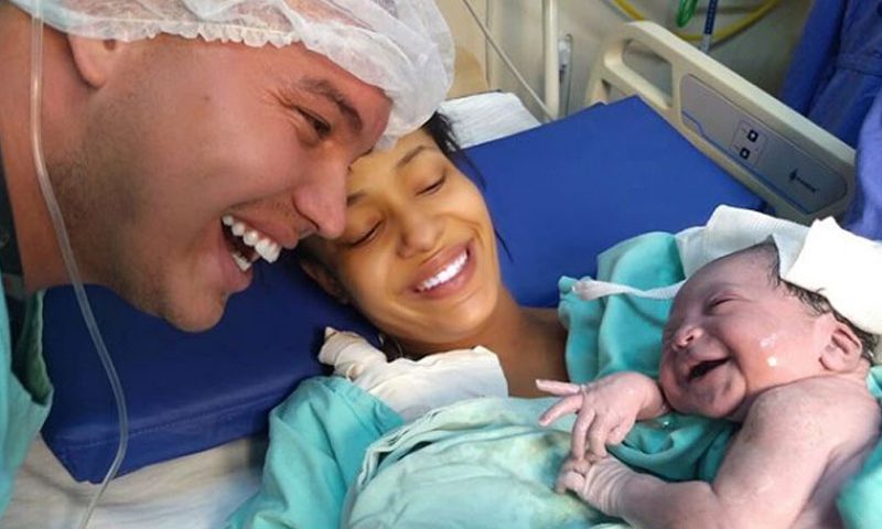 Filha sorri para o pai logo após o parto. Fotografia fica viral nas redes sociais